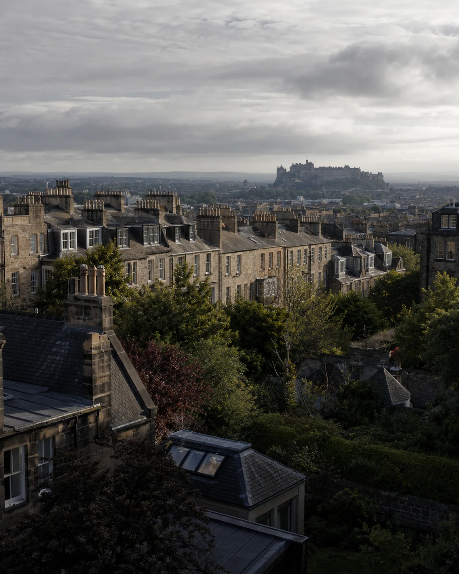Edinburgh Castle on the hill above Georgian tenement rooftops and chimneys.