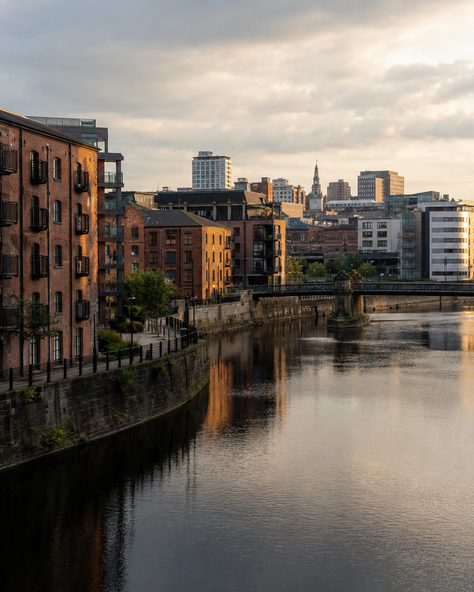 Leeds waterfront: brick warehouses and modern apartments beside the river at sunset.